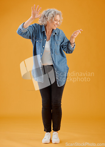 Image of Fun, happy and cheerful woman dancing, celebrating and enjoying life alone against an orange background. Senior woman feeling excited, joyful and playful with dressed stylish, trendy and fashionable