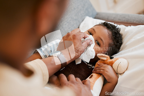 Image of Sick, ill and unwell little boy suffering from cold, flu or covid and lying on the sofa at home while blowing his nose with dad. Cute son with a runny nose and resting in the living room from above