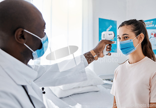 Image of Covid temperature testing at the hospital by a doctor of a female patient wearing masks and using an infrared thermometer. Medical professional checking a female for covid19 virus or infection