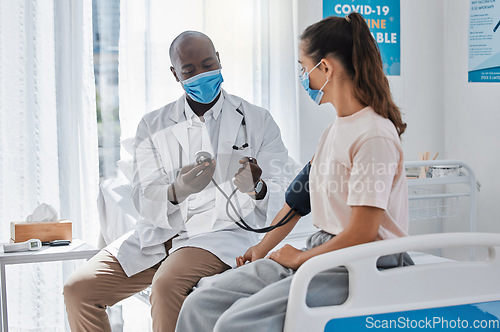 Image of Doctor, blood pressure and healthcare medic checking womans hypertension levels on the hospital bed. People, healthy or sick patient doing medical test in covid 19 mask for pandemic safety protocol