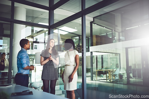 Image of Business team standing and talking inside of the office together. Meeting and open discussion with colleagues in the workplace. Corporate mentor coaching and assisting new employees at the company.