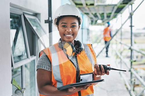 Image of Portrait of proud black construction worker leading with power while managing site logistics on tablet. Happy female engineer supervising a building project and inspection of architectural details