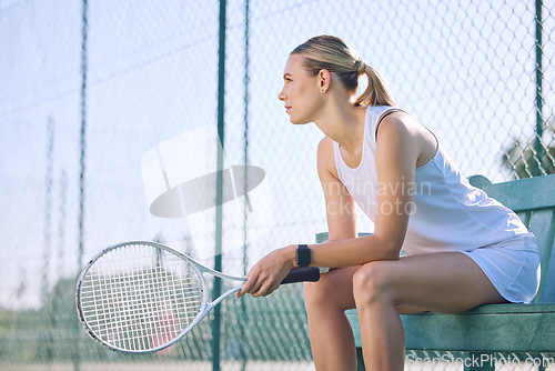 Image of Professional tennis player or sports woman with a racket gear or equipment sitting on a bench, taking a break or waiting for match to start. Active girl with a goal or vision for competition success