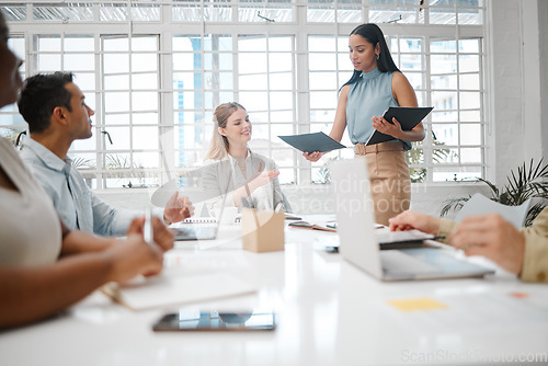 Image of Female intern, assistant or employee handing out an information document to a team during a boardroom meeting. Group of business people discussing the mission, vision and strategy for company growth