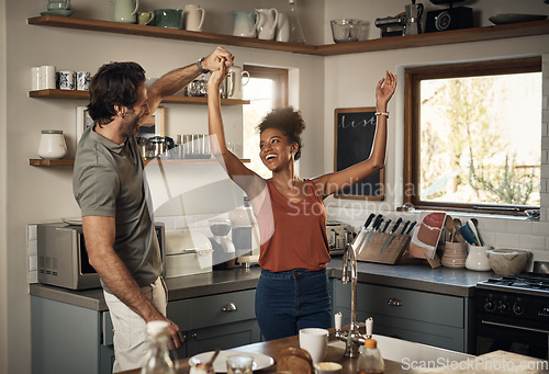 Image of Happy interracial couple dancing, having fun and bonding together in the kitchen at home. Carefree, cheerful and loving husband and wife being playful, doing a dance and enjoying a romantic day