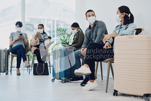 Image of Group of people traveling during covid waiting in line at an airport lounge wearing protective masks. Tourists sitting in a queue at a public travel facility during coronavirus pandemic