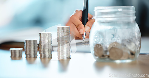 Image of Hands of a bank teller, accountant or finance worker counting coins, money and writing down the numbers for a audit. Closeup of a financial advisor analyzing a clients expenses, savings or capital