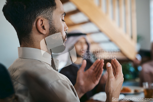 Image of Muslim, praying and religion while sitting with family and say a dua or prayer before breaking fast during the holy month of Ramadan. Religious man lifting his hands to pray during eid or iftar meal