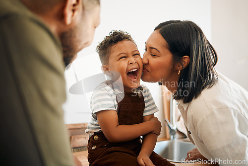 Image of Happy boy getting a kiss by caring mother, bonding and laughing during family time at home. Young parents sharing a sweet moment of parenthood with their playful child, relaxing and carefree together