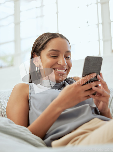 Image of Happy, relaxed and modern woman with a phone texting, checking social media app or reading message online while relaxing on sofa indoors at home. Casual female browsing the internet for funny content