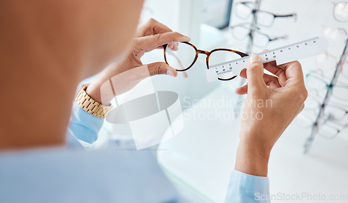 Image of Optician or optometrist hands measuring and preparing pair of glasses and frame with optic ruler tool. Eye doctor or ophthalmologist determines visual or vision lens size using special eyewear scale.