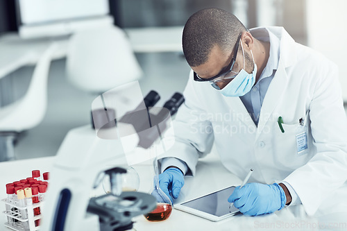 Image of Scientist, researcher and medical worker using a tablet for innovation and research while wearing a face mask in a lab. Male chemist working to find a cure for covid virus in a science facility