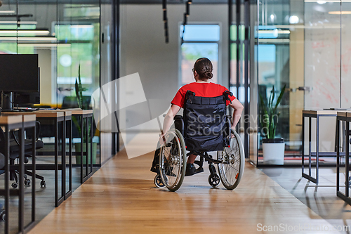 Image of A modern young businesswoman in a wheelchair is surrounded by an inclusive workspace with glass-walled offices, embodying determination and innovation in the business world