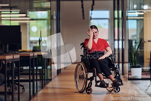 Image of A modern young businesswoman in a wheelchair is surrounded by an inclusive workspace with glass-walled offices, embodying determination and innovation in the business world