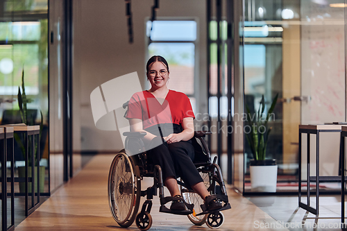 Image of A modern young businesswoman in a wheelchair is surrounded by an inclusive workspace with glass-walled offices, embodying determination and innovation in the business world