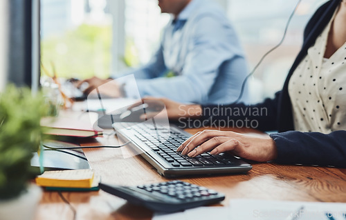 Image of Hands of woman typing on keyboard in a call center for client data. Closeup of busy woman in customer service giving clients online support through communication with colleague in the background.