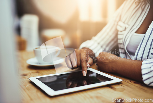 Image of African woman working on a tablet, sitting in a cafe with coffee alone. Businesswoman using technology to do her job at her desk in the office. Lady casually scrolling the internet in a restaurant.