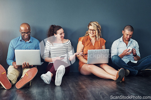 Image of Smiling, diverse group of casual and modern business people with their digital devices on social media networking apps. Happy, connected team of colleagues sitting, working on laptop pcs and phones