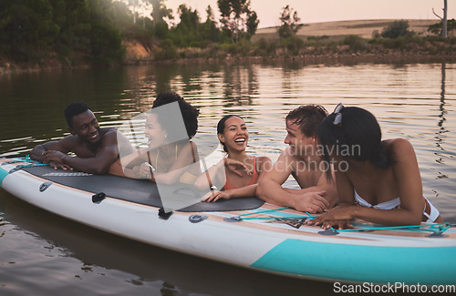Image of Friends, vacation and having fun while leaning on a paddle board and talking in a lake. Happy and diverse people laughing while enjoying the water and friendship on their holiday and nature travel