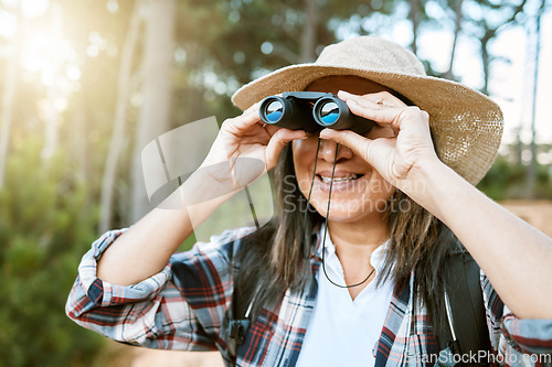 Image of Female tourist hiking, looking through binoculars at wild birds in the trees. Happy, carefree and mature woman on nature walk, enjoying the view. Outdoor holiday time to promote health and wellness.