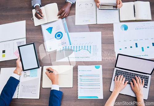 Image of Financial strategy, growth analysis and planning in meeting with laptop, tablet and graph charts in office. Above desk of diverse group business people analyzing marketing data, report and profit