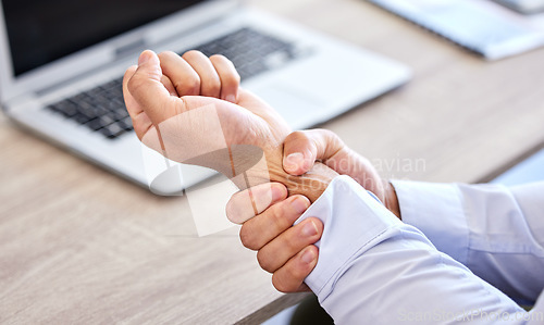 Image of Business man with bad wrist pain in the hand after an injury and ache while in the office. Closeup of a corporate male with a painful strain, hurtful and sore sitting at his desk