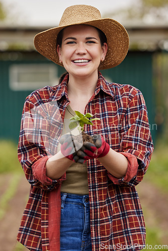 Image of Sustainable farmer holding a plant or seedling outdoors smiling and happy about her organic farm or garden. Young female nature activist that is passionate about sustainability standing on farmland