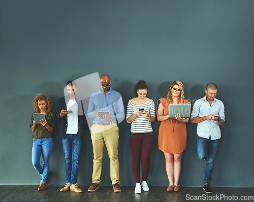 Image of Diverse group of people browsing social media on a phone, tablet and laptop in studio on a grey background. Networking, surfing the internet and posting online with wireless technology and copyspace