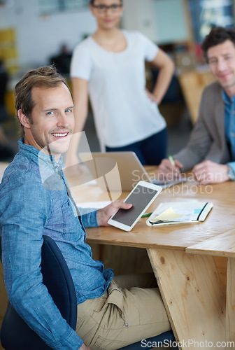 Image of Smiling marketing manager browsing the internet on a digital tablet in an office. Handsome and happy professional researching creative ideas to promote and advertise a startup on social media