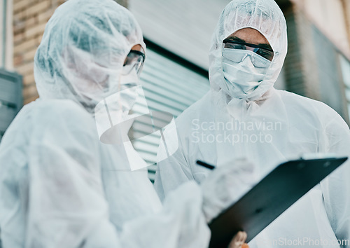 Image of Healthcare workers wearing protective hazmat suits writing a medical report about covid cases or statistics. First responders filling in a form after doing a safety health check for coronavirus