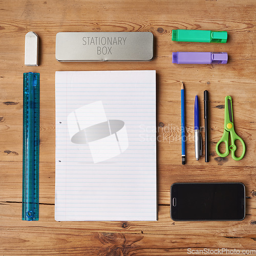 Image of School supplies, stationary or equipment for young working and studying students top view. Assortment, variety or array of education essentials items including a phone and notebook on a wooden desk
