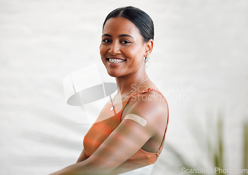 Image of Plaster, vaccinated and covid treatment on a womans arm as shes smiling, happy and proud to stay safe. Healthy female with a band aid protecting against corona virus by taking a vaccine injection