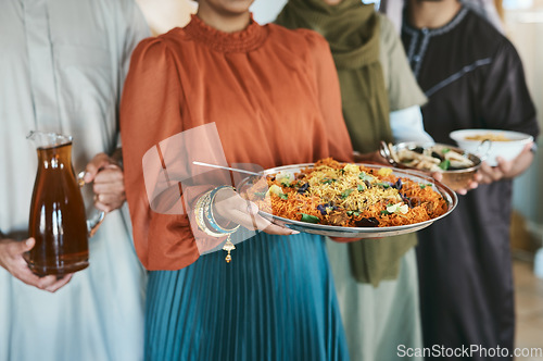 Image of Ramadan, Eid and iftar with a muslim family holding food and drink to break their fast at home together. Closeup of rice and curry in the hands of a woman with people holding other meals and juice