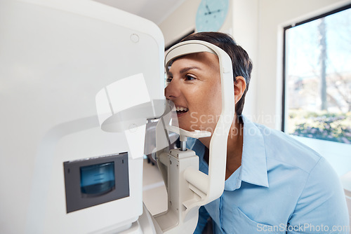 Image of An eye test, exam or screening for vision and eyesight at the optometrist or optician with a young woman. Testing her sight with an automated refractor for prescription glasses or contact lenses