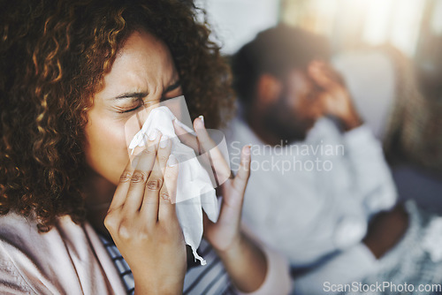 Image of Ill or sick woman with allergy, sinus infection sneezing in tissue or blowing nose during flu season at home. Sick girl caught a bad cold showing symptoms of covid, or suffering from a virus disease