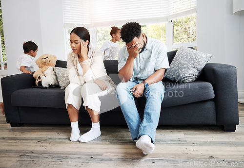 Image of Sad, unhappy and stressed parents sitting on a couch near their children at home after an argument. Frustrated, tired and annoyed mom and dad are angry at hyperactive, noisy and naughty kids
