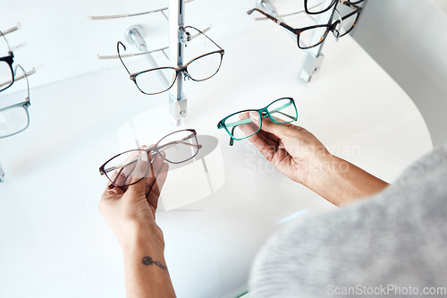 Image of Buying, looking and shopping for glasses at a retail eyewear store and optometrist inside. Customer holding shop stock trying to decide on a new modern style, trendy and stylish frames to buy on sale