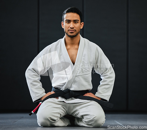 Image of . Male coach ready for karate training at fitness studio, looking serious at dojo practice in gym and sitting on the floor at a self defense class. Portrait of tough, healthy and active trainer.