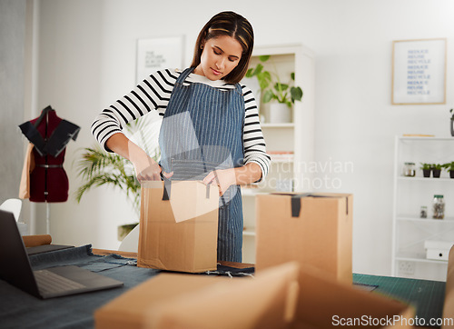 Image of Creative designer packing order in box, tailor organizing package for courier delivery service and closing product parcel working at design studio, boutique or shop. Business owner unpacking supplies