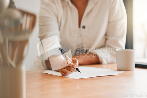 Image of Writing, paperwork and contract with a woman holding a pen and filling out an application form in her kitchen at home. Insurance, tax and accounting while managing finance and the household budget