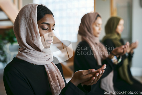 Image of Praying, muslim and young women group practicing arabic, holy and islamic religion indoors. Females wearing a hijab while kneeling to practice a quiet, spiritual and worship prayer inside in silence