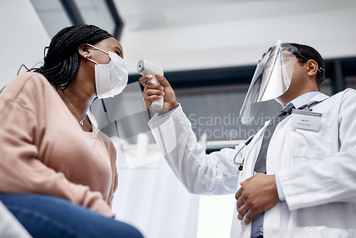 Image of Covid screening with a doctor measuring temperature of a patient using an infrared thermometer during an appointment or checkup. Female getting tested for corona virus and wearing a mask from below