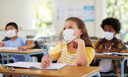 Image of Focused young girl in school after covid pandemic, sitting and listening in classroom while taking notes. Small child looking at board, learning and thinking for her education with other students