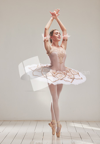Image of Female ballerina doing ballet dance, dancing or performing during a practice rehearsal in studio. Young dancer or artist in a tutu costume dress and shoes doing pointe technique on toes performance