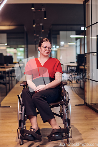 Image of A modern young businesswoman in a wheelchair is surrounded by an inclusive workspace with glass-walled offices, embodying determination and innovation in the business world