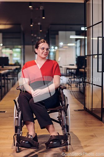 Image of A modern young businesswoman in a wheelchair is surrounded by an inclusive workspace with glass-walled offices, embodying determination and innovation in the business world