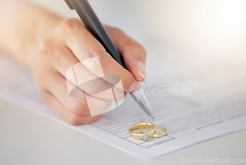 Image of .Woman hand signing legal divorce documents, deal or paper contract in a lawyer office with ring placed on table. Person writing signature on marriage paperwork after agreement at family law office.