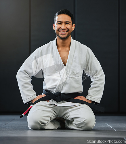 Image of Mma, karate and training with a young man kneeling in a gym, health studio or dojo in his gi or uniform. Portrait of a male training, exercising and learning self defense in a workout and fight class