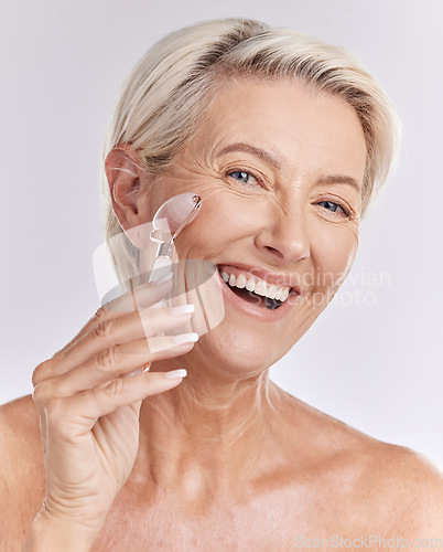 Image of Mature, portrait and woman using rose roller on face for skincare massage and beauty spa routine. Feminine, selfcare and cosmetics for anti ageing facial treatment with white studio background.