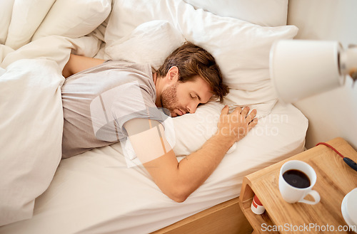 Image of Sleeping, resting and sleepy man lying in bed with his eyes closed in a deep sleep in his bedroom. Rest, relax and tired person at home dreaming and relaxing at his house taking a late morning nap